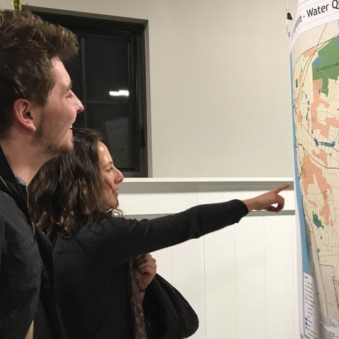 A man and woman look at and point to a map at a public meeting. Photo by L Heady